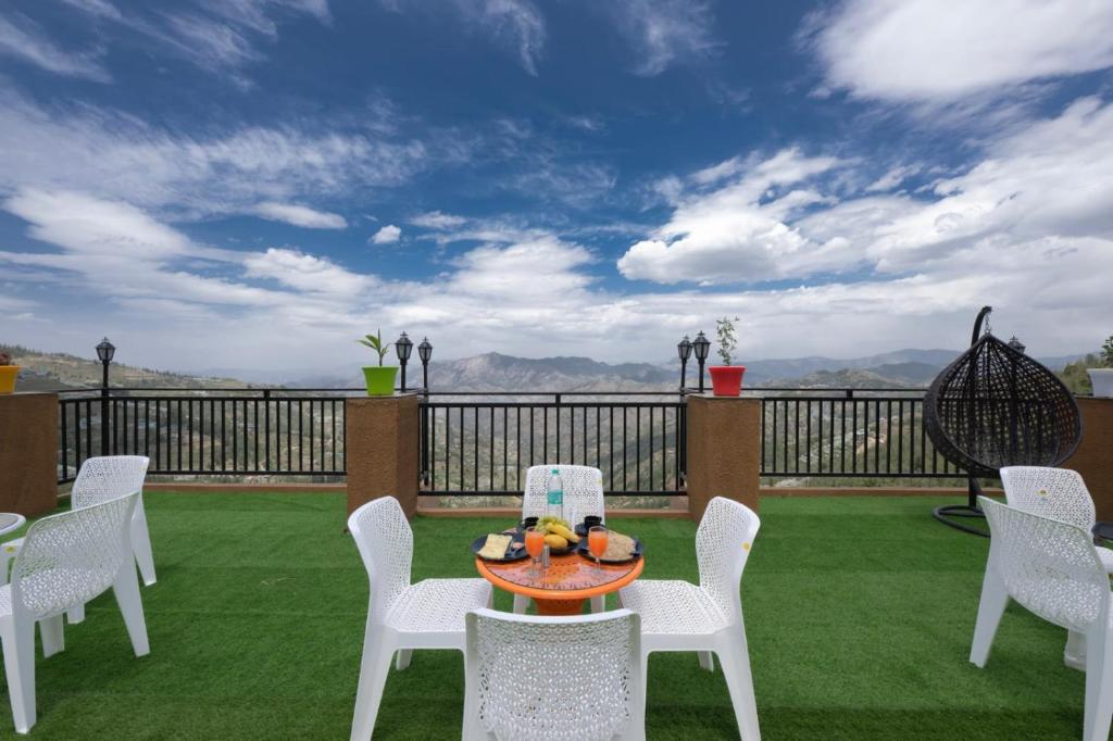 a patio with white chairs and a table with fruit on it at The Yoga Retreat l Place for Yoga I Meditation I Shanti & Dhayan l Vacations I Family Events I Kufri by Exotic Stays in Shimla