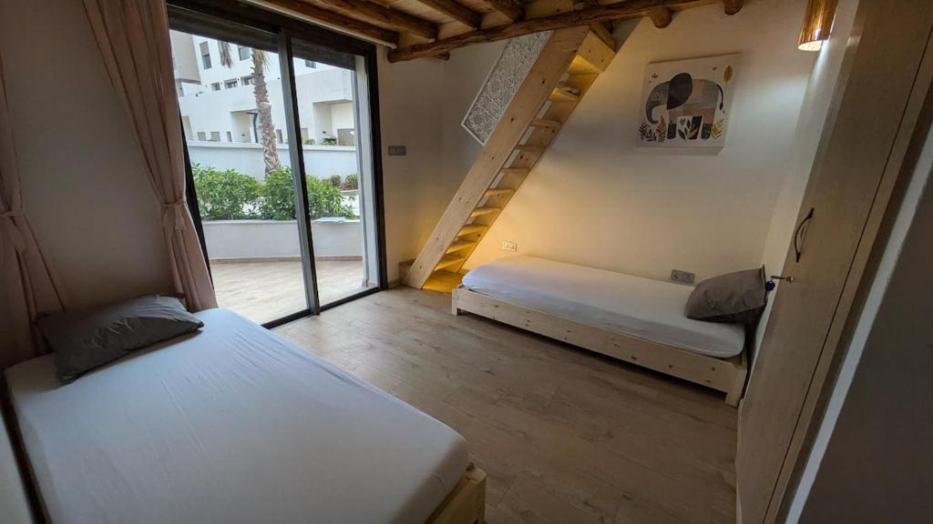 a small room with two beds and a large window at Appt neuf Zenata- 2 chambres et Mezzanine - Piscine in Aïn Harrouda