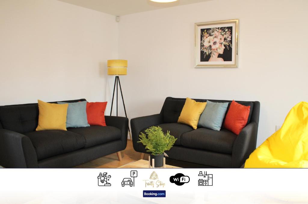 a living room with two black couches with colorful pillows at 3 Bedroom House By Trinity Stays Short Lets & Serviced Accommodation Cambridge With Free WiFi & Parking in Cambridge