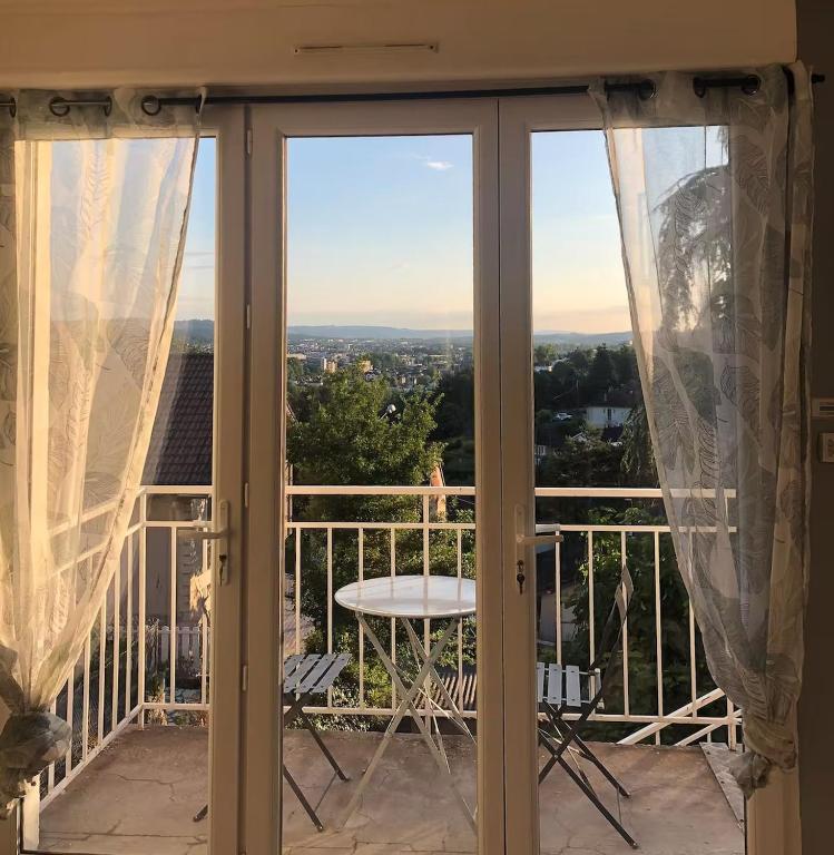 un balcon avec une table et une vue sur une ville dans l'établissement Joli petit appartement sur les hauteurs de BRIVE, à Buissou