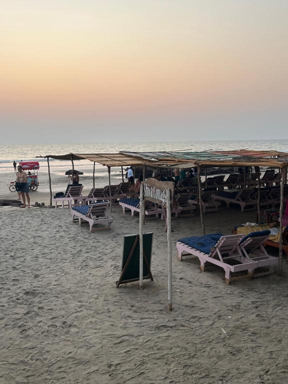 a group of chairs and umbrellas on a beach at Shiva Cottages in Mandrem