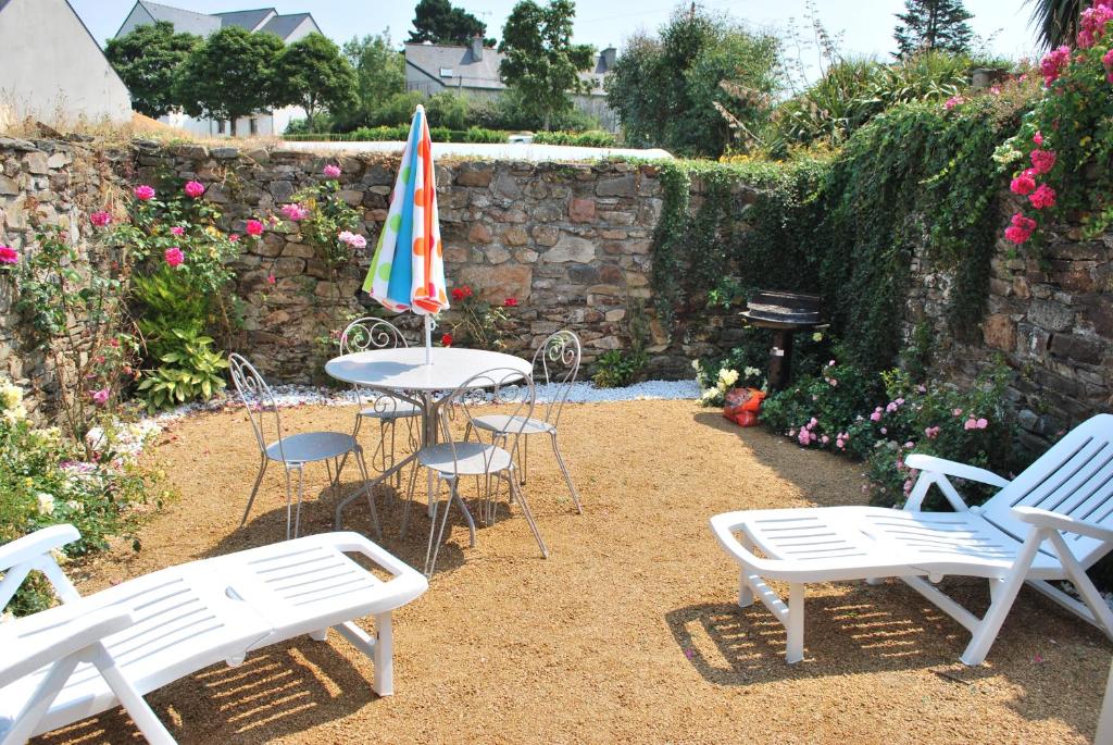 un patio avec une table, des chaises et un parasol dans l'établissement Gîte de SAINT RIOM, à Paimpol