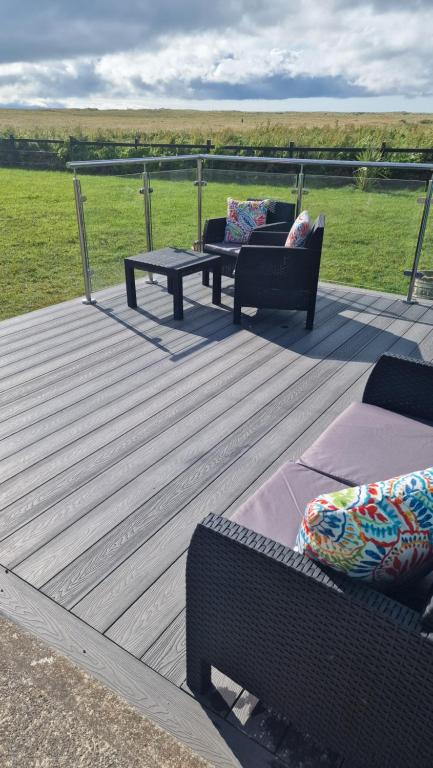 a deck with two chairs and a table and benches at Shanadune in Tralee