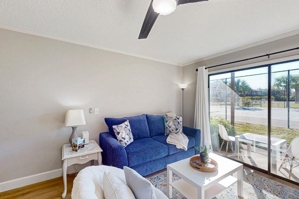 een woonkamer met een blauwe bank en een tafel bij Cozy condo with shared pool, close to historic downtown st augustine in St. Augustine