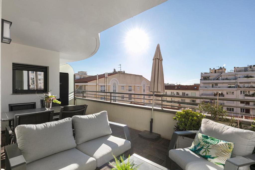 - un balcon avec un canapé, une table et un parasol dans l'établissement Suite Relax Five Stars Holiday House, à Nice