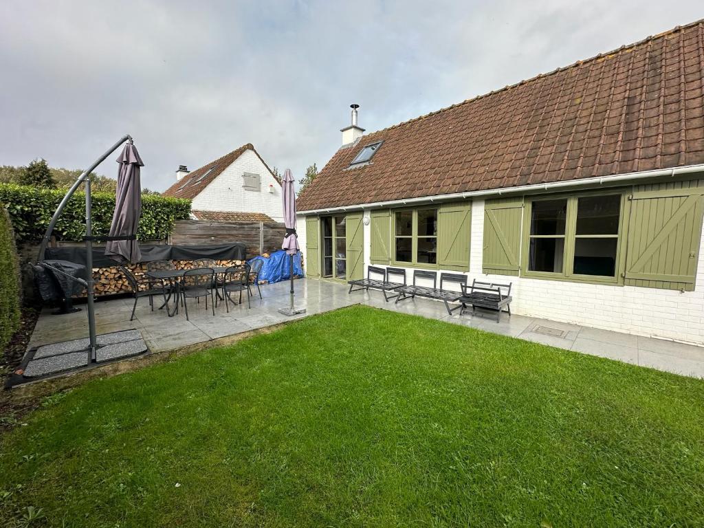 un cortile con patio e prato di Huisje aan de zee Duinendaele a De Panne