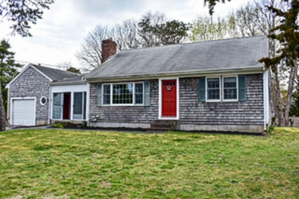 a house with a red door on a yard at Captain's Escape in South Yarmouth