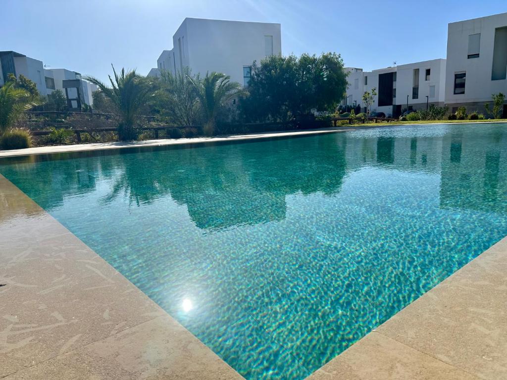 una piscina con acqua blu di fronte agli edifici di La perle de Taghazout Bay a Taghazout