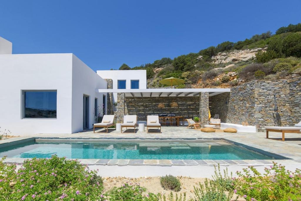 a villa with a swimming pool and a house at Villa Lefkos Lofos in Paros in Kóstos