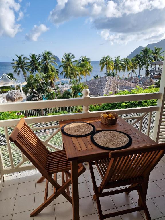 a wooden table and chairs on a balcony with the ocean at Ti Dyaman - Studio vue mer & accès piscine gratuit in Le Diamant