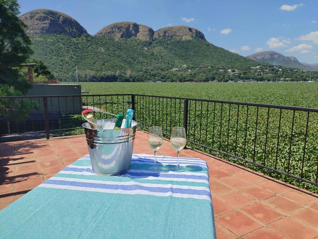 a table with two wine glasses and a bucket on a balcony at Wakanda on Hartbeespoort Dam in Hartbeespoort