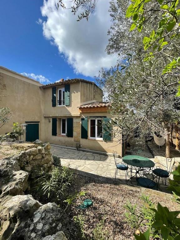 une maison avec une table et des chaises dans une cour dans l'établissement Charmante maison au coeur du village - 2 chambres, à Lambesc