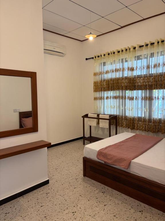ein Schlafzimmer mit einem Bett, einem Spiegel und einem Fenster in der Unterkunft The Grace Cottage - Negombo in Dagonna