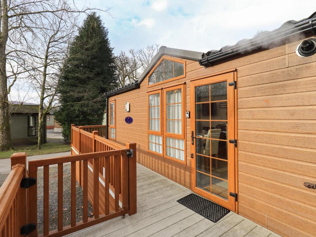 a wooden cabin with a large glass door on a deck at Squirrels Snug in Windermere