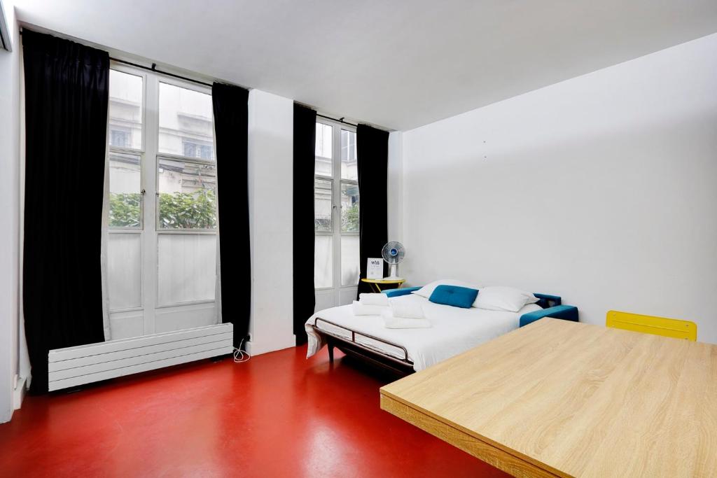 une chambre avec un lit et une grande fenêtre dans l'établissement Studio Louvre Opera, à Paris