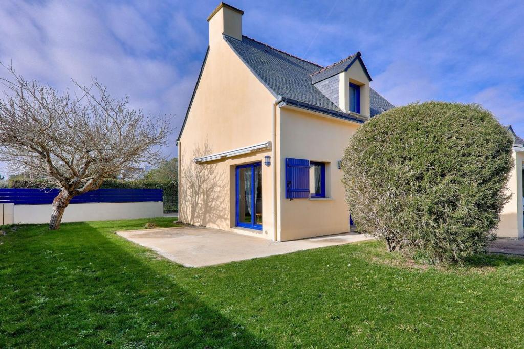 une maison blanche avec des fenêtres bleues et un arbre dans l'établissement À 500m de la plage, maison pour 6 avec jardin, à Sarzeau