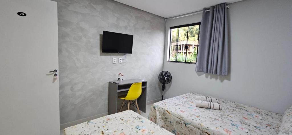 a bedroom with two beds and a desk and a television at Hotel Real in Ouro Preto