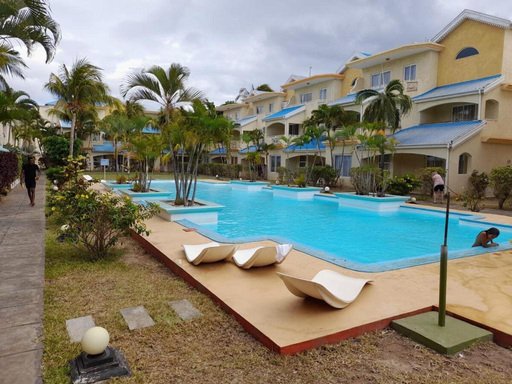 a pool at a resort with lounge chairs and palm trees at BEST location Service Apartment - FLIC EN FLAC in Flic-en-Flac