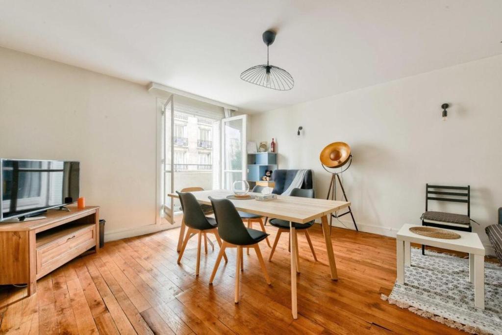 - un salon avec une table, des chaises et une télévision dans l'établissement T2 with Stunning Balcony 55m2 Paris 17, à Paris