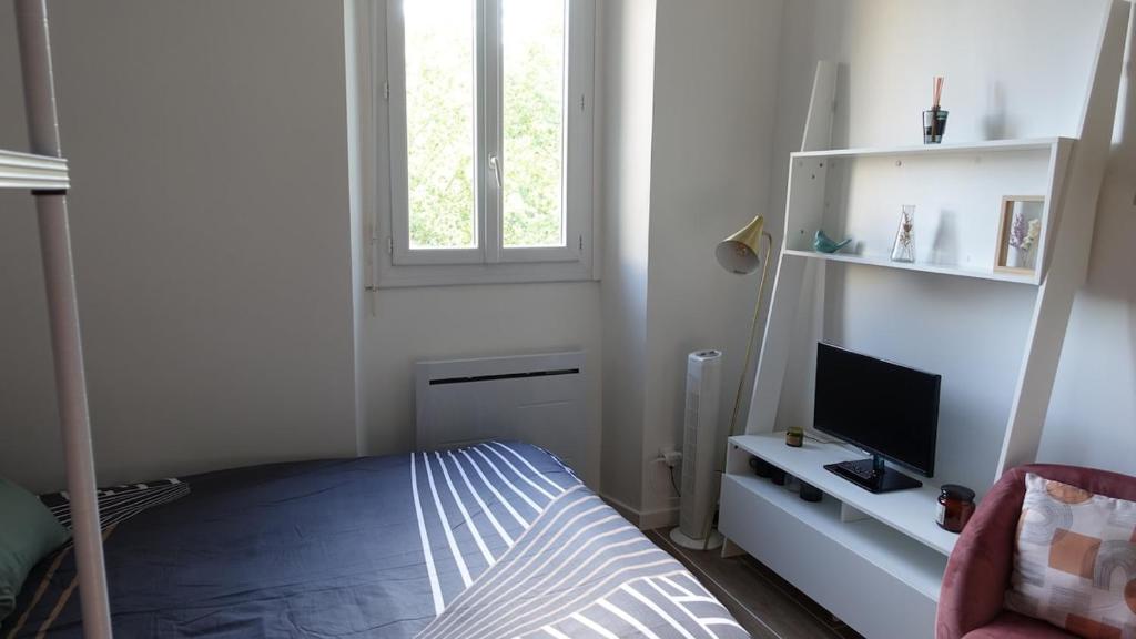 une chambre avec un lit et un bureau avec une télévision dans l'établissement Central, cozy and warm, à Toulouse