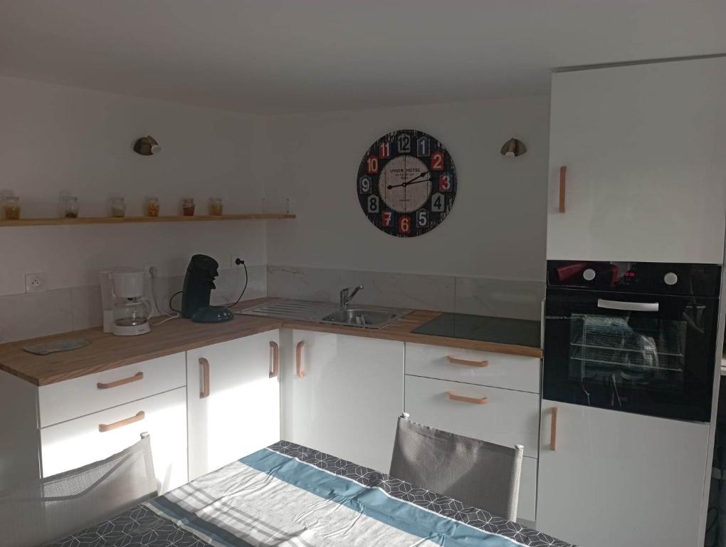 a kitchen with white cabinets and a clock on the wall at Ti Louker - Appartement à 300m du Port in Locmiquélic