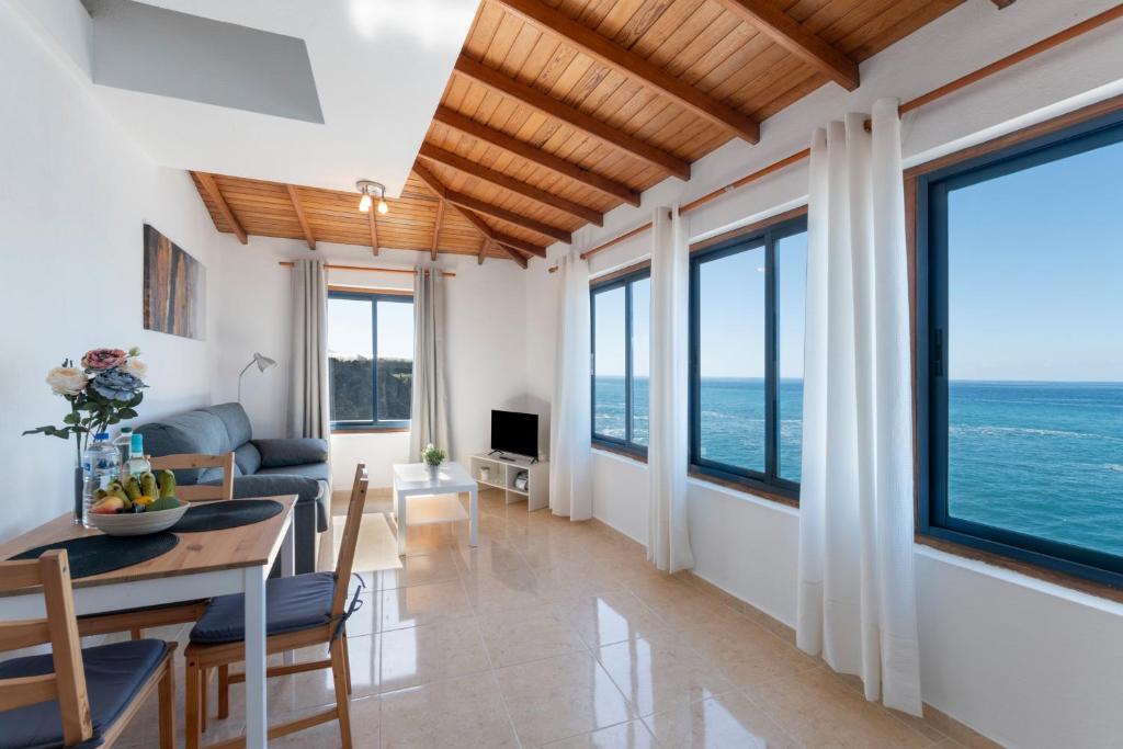 Una sala de estar con una mesa y sillas y el océano. en La Bayana Apartments - 8, en Puerto Naos