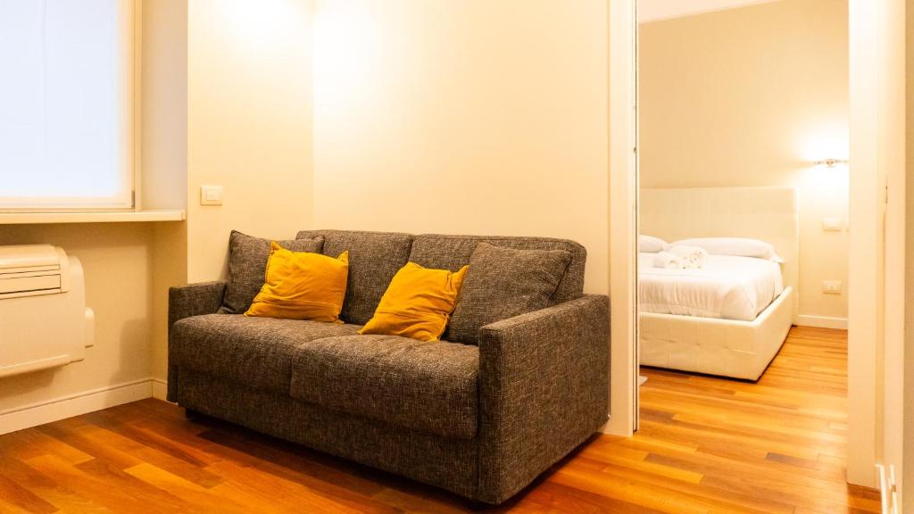 a couch with two yellow pillows in a room at Luxury Flat - WiFi, AC, Walk to Brera & Duomo in Milan