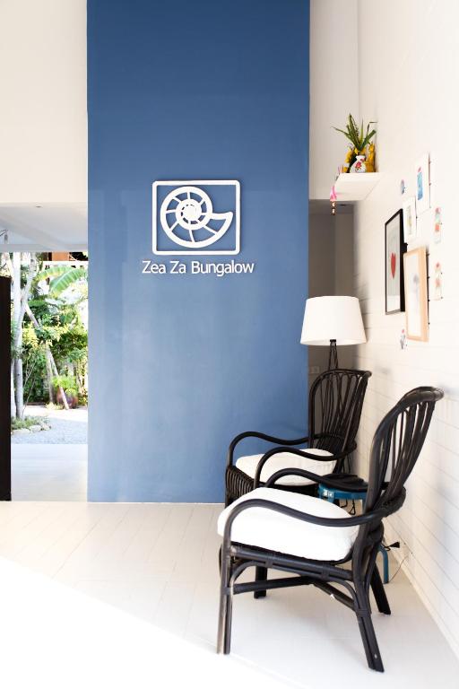 two chairs and a lamp in front of a blue wall at Zea Za Bungalow in Hua Hin