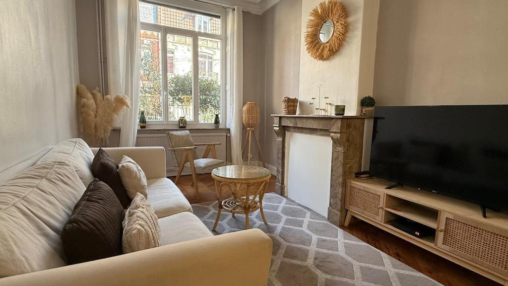 un salon avec un canapé et une télévision dans l'établissement Maison la Madeleine Romarin !, à Lille