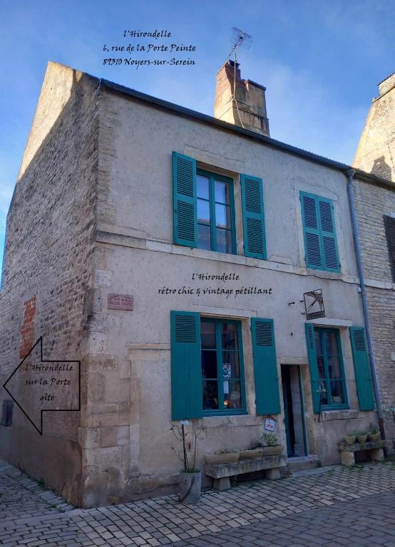 Un vieux bâtiment avec des volets verts dans l'établissement l'Hirondelle sur la Porte, à Noyers-sur-Serein