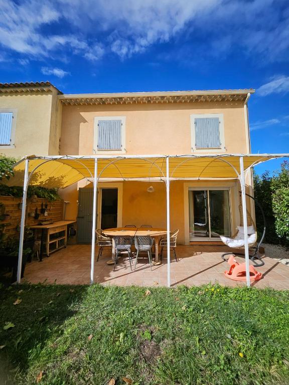 une terrasse avec une table et des chaises sous une tente dans l'établissement Maison des Fenaisons, à Entraigues-sur-la-Sorgue