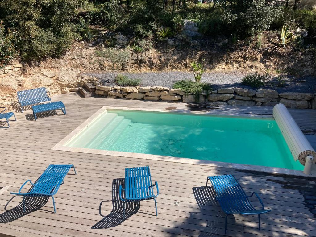 une piscine avec des chaises bleues et une terrasse avec une piscine dans l'établissement Villa contemporaine avec piscine, à Sussargues