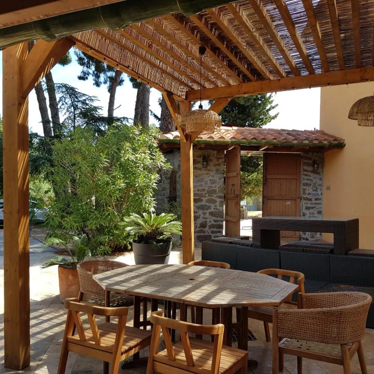 une table et des chaises en bois sous une pergola en bois dans l'établissement la Cigale, à Collioure