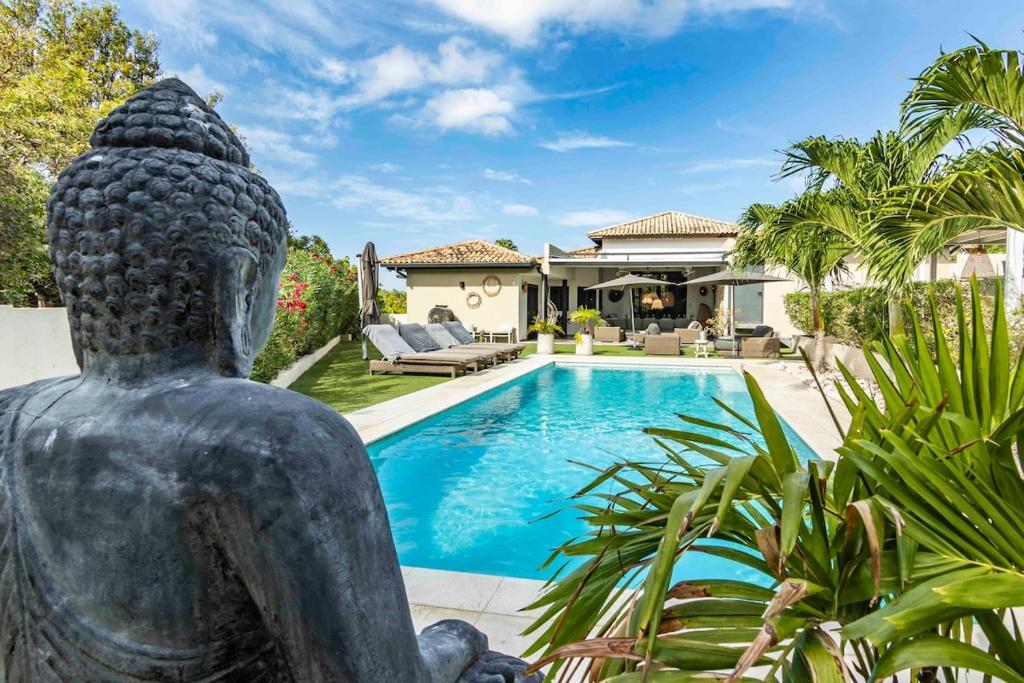 a home with a statue in front of a swimming pool at Villa Leon Spacious Tropical Villa with pool and outdoor kitchen in Jan Thiel
