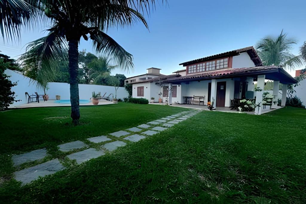 a house with a palm tree in front of a yard at Linda casa com estilo buziana in Búzios