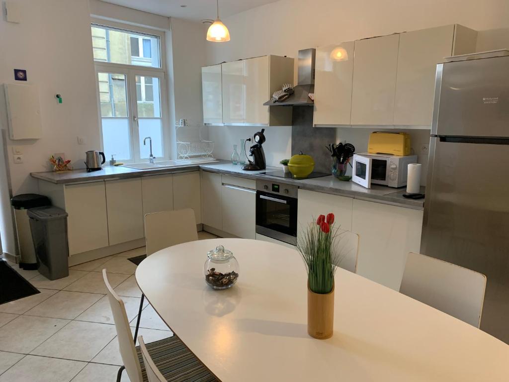 a kitchen with a table with a vase of flowers on it at L'echo des notes in Saint-Omer