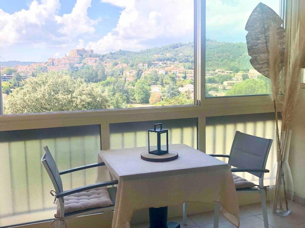 une table et des chaises dans une pièce avec une fenêtre dans l'établissement Grand Studio proche cure&village, à Gréoux-les-Bains