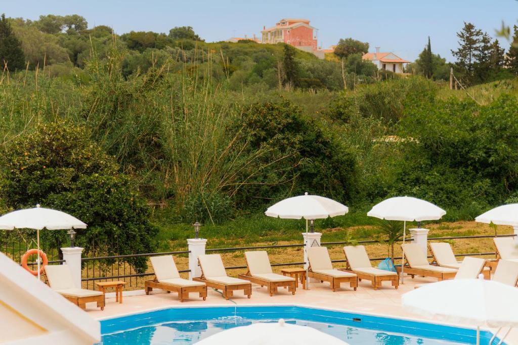 a group of chairs and umbrellas next to a swimming pool at Villa INVA Korfu in Kavos