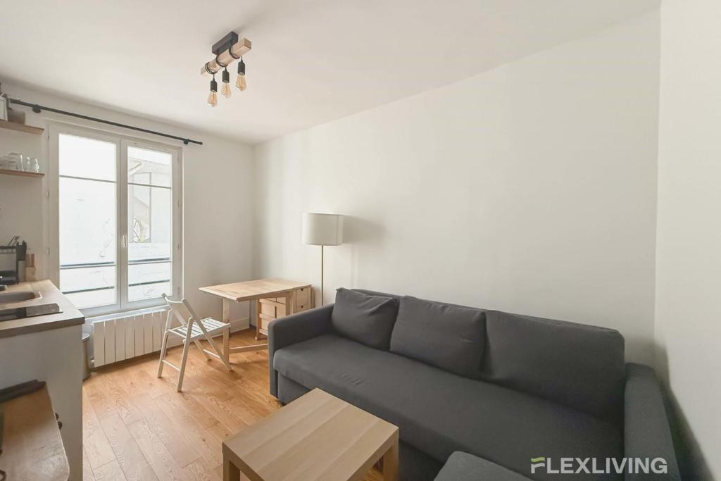 un salon avec un canapé et une table dans l'établissement Boucry - Charming and Bright One-Bedroom Apartment in the Heart of the 18th, à Paris