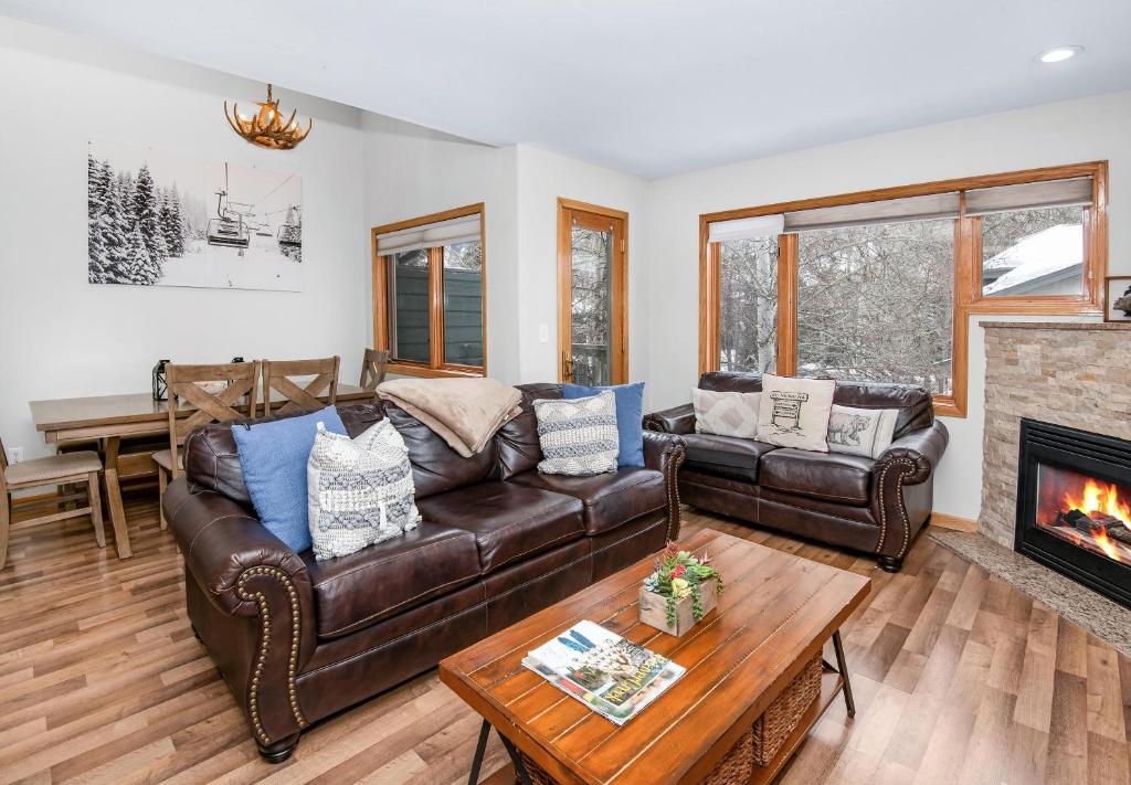 a living room with a leather couch and a fireplace at Greenbrier Townhouse #25 in Avon