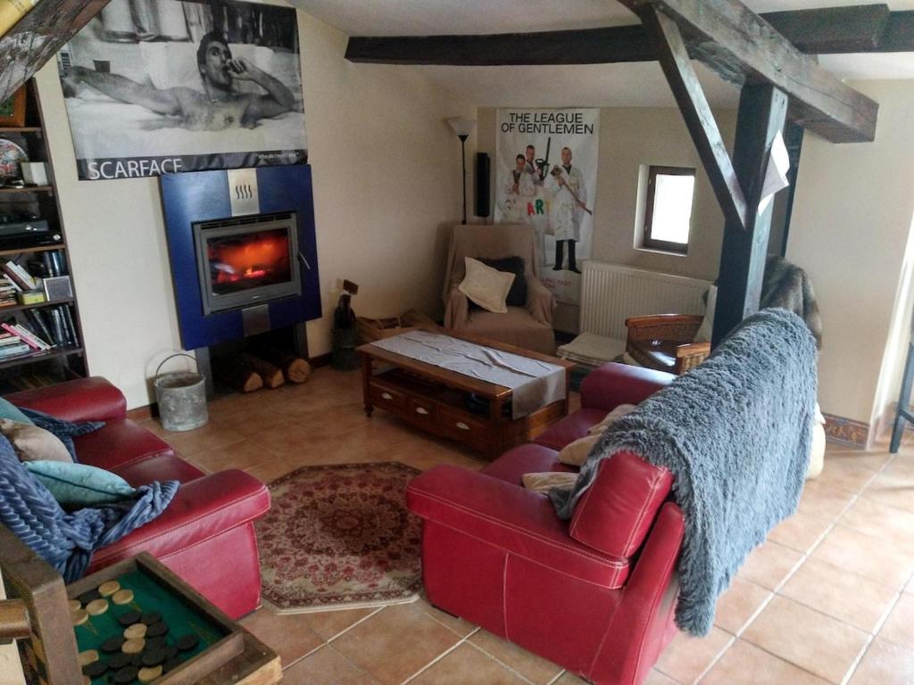 - un salon avec deux chaises rouges et une cheminée dans l'établissement Maison de famille, à Saint-Jean-de-Sauves