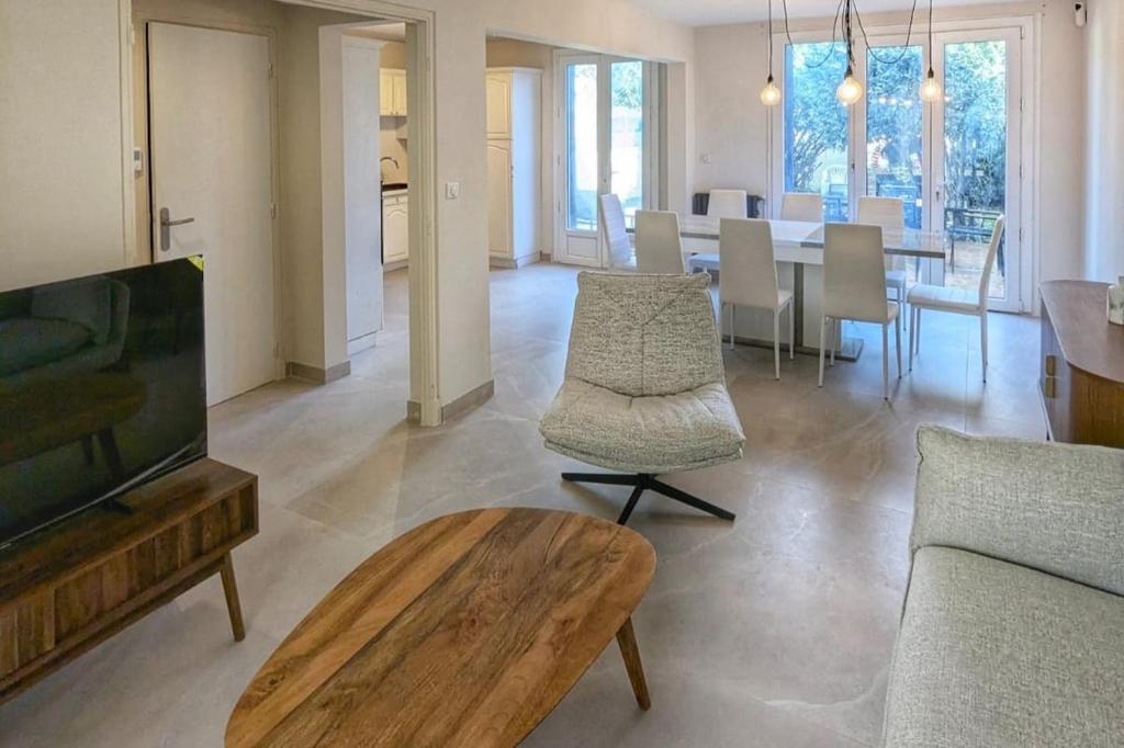 Il comprend un salon doté d'une télévision et d'une table avec des chaises. dans l'établissement Maison lumineuse avec Jardin, à Montpellier