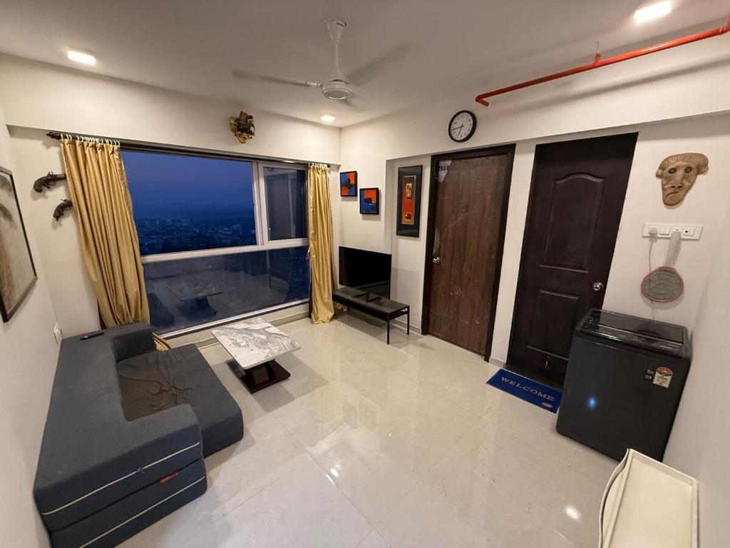 a living room with a couch and a large window at Creek View Studio Apartment in Mumbai