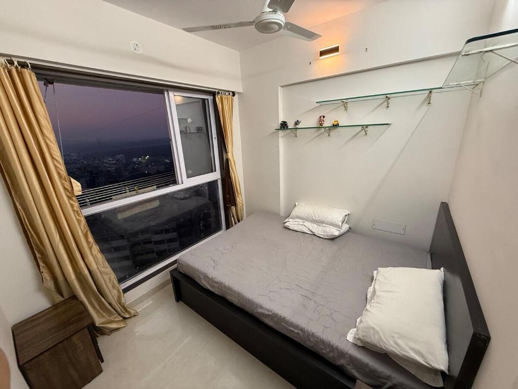 a small bedroom with a bed and a large window at Creek View Studio Apartment in Mumbai