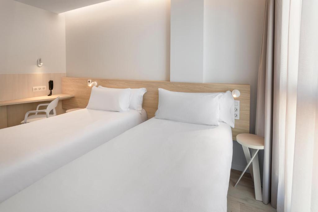 a bedroom with two white beds and a desk at B&B HOTEL Alicante Centro in Alicante