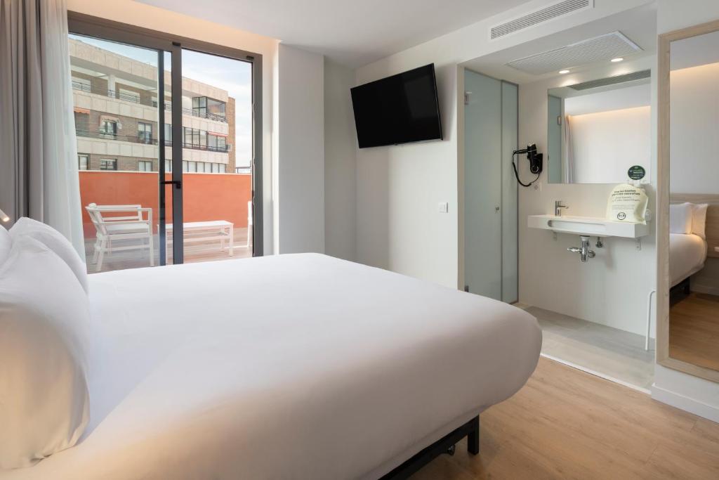 a bedroom with a white bed and a bathroom at B&B HOTEL Alicante Centro in Alicante