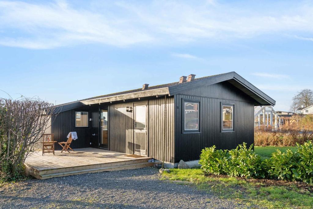 a black tiny house with a wooden deck at Cozy Summer House Close To Beach And Nature in Rønde
