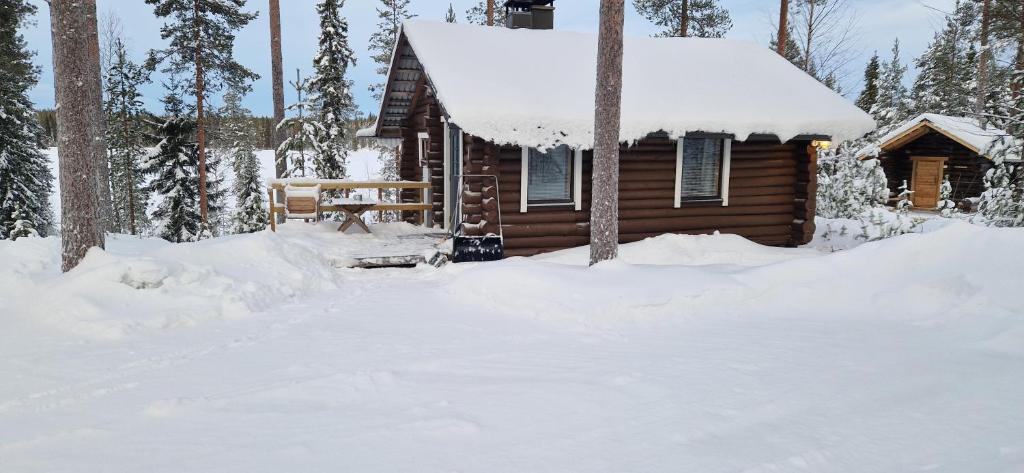a log cabin in the snow with a bench at Ukonloma Aimola in Rovaniemi