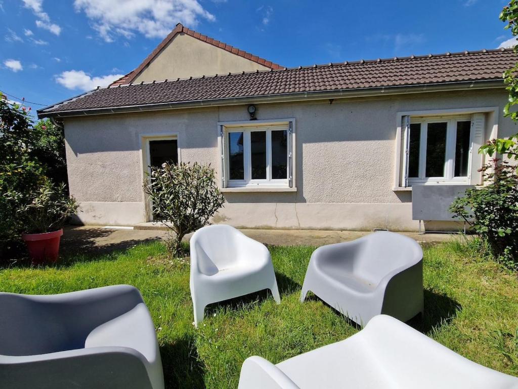un groupe de chaises blanches dans l'herbe devant une maison dans l'établissement Le Cocon de Cécile - Close to Paris-La Défense, à Bezons