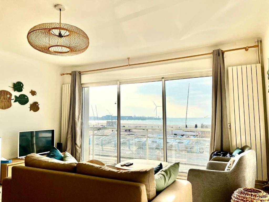 un salon avec un canapé et une grande fenêtre dans l'établissement Le Face Mer, à Boulogne-sur-Mer